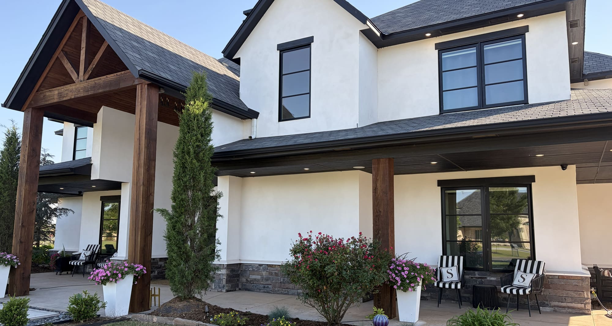 White stucco home with dark trim and a timber-framed porch